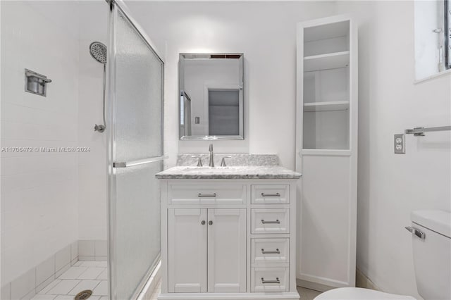 bathroom featuring tile patterned flooring, vanity, a shower with shower door, and toilet