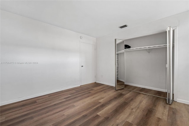 unfurnished bedroom with dark hardwood / wood-style floors and a closet