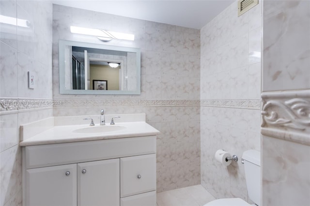 bathroom with vanity, toilet, and tile walls