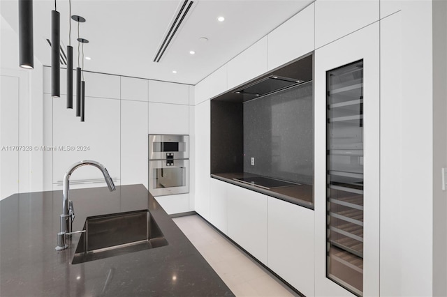 kitchen featuring dark stone counters, sink, white cabinets, and stainless steel double oven