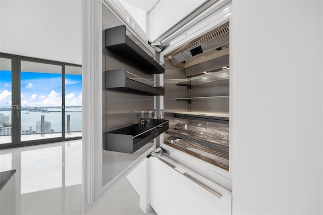 kitchen featuring white cabinets, expansive windows, and a water view