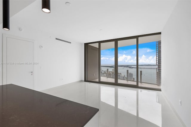 unfurnished room with a water view and a wall of windows