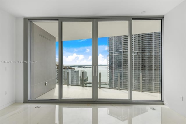 spare room with tile patterned flooring, a water view, and a wall of windows