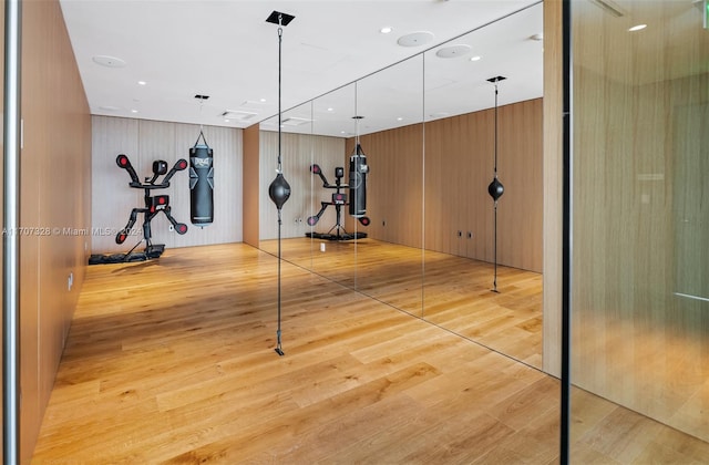 workout area featuring wood walls and light wood-type flooring