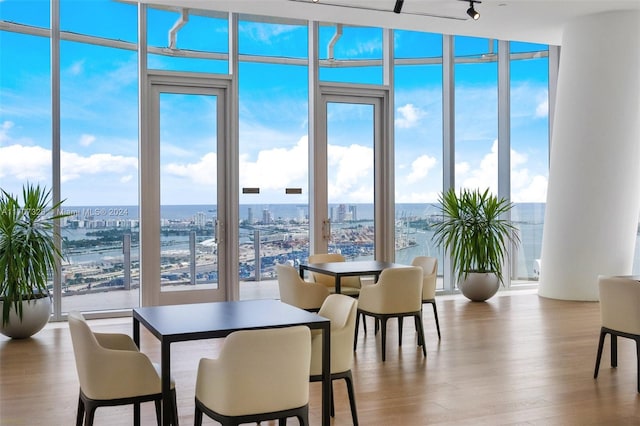 dining space featuring floor to ceiling windows, a water view, and light hardwood / wood-style flooring