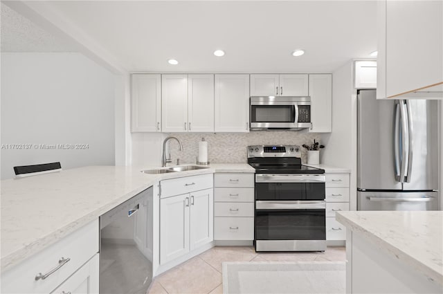 kitchen with appliances with stainless steel finishes, light stone counters, sink, white cabinetry, and light tile patterned flooring