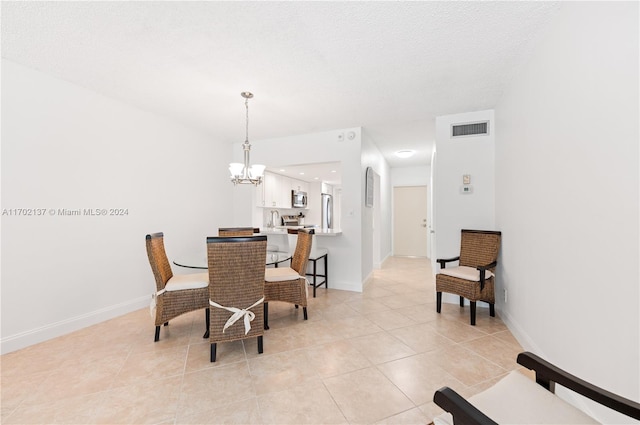 dining area featuring a chandelier, light tile patterned floors, and a textured ceiling