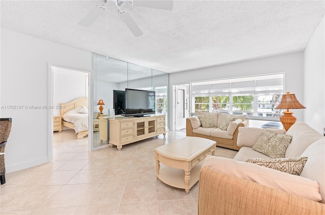 living room featuring ceiling fan, light tile patterned floors, and a textured ceiling