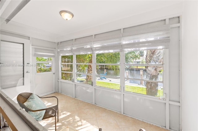 sunroom featuring a water view