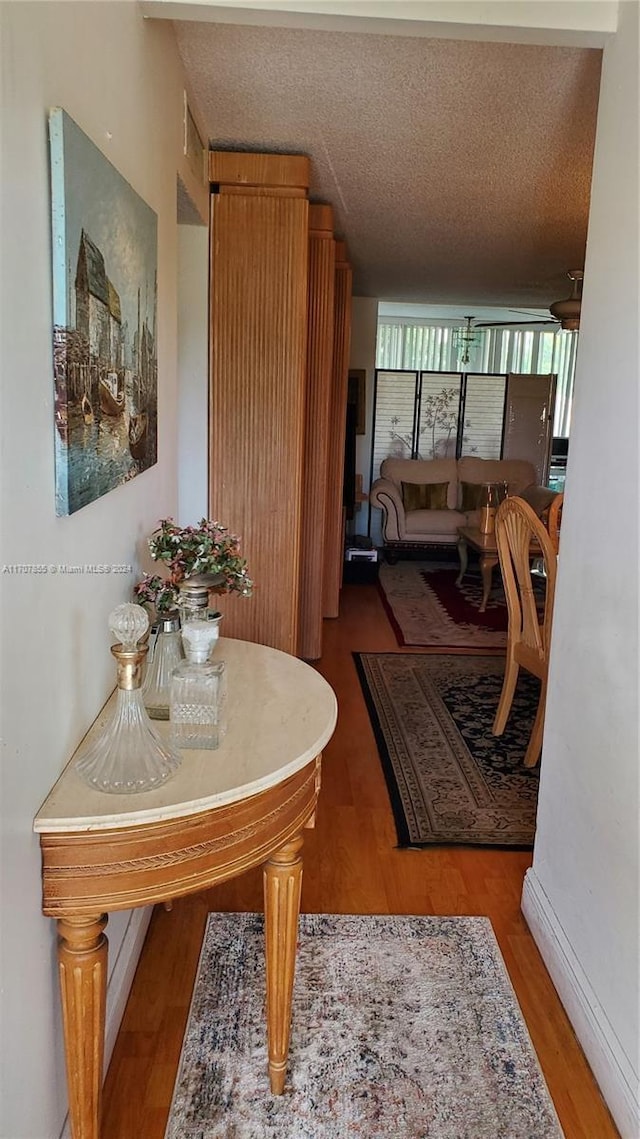 hall with hardwood / wood-style floors and a textured ceiling