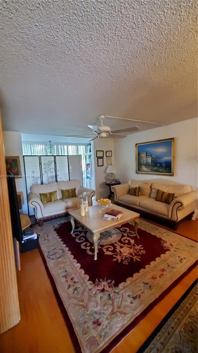 living room with hardwood / wood-style floors, a textured ceiling, and ceiling fan