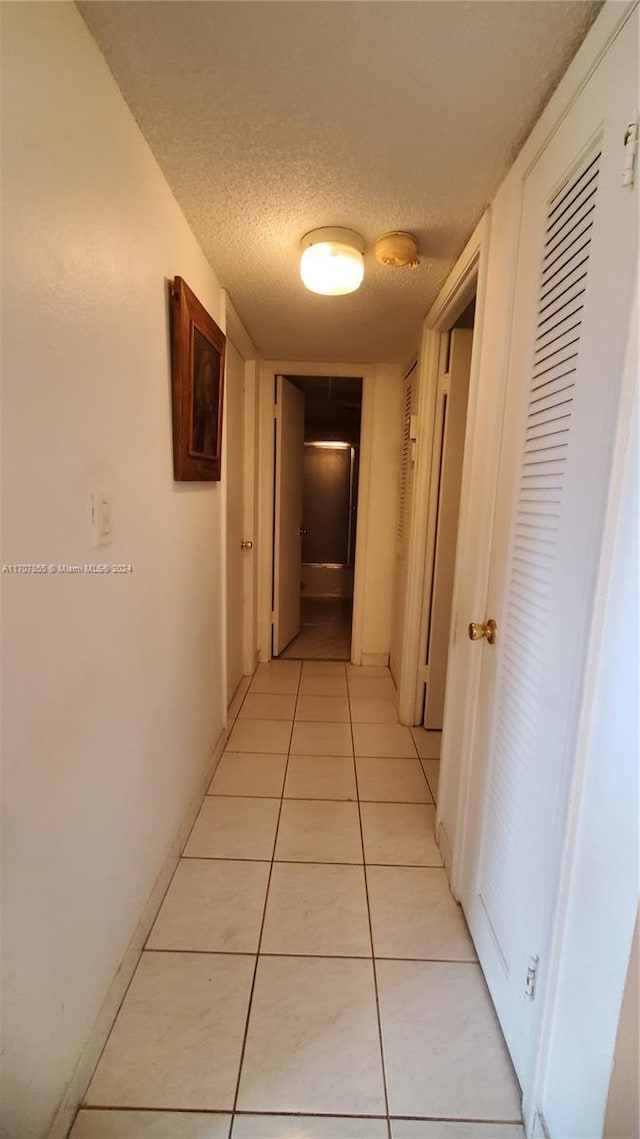 corridor with light tile patterned floors and a textured ceiling