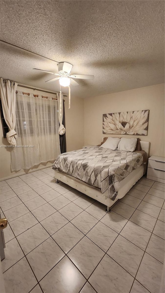 unfurnished bedroom featuring light tile patterned floors, a textured ceiling, and ceiling fan