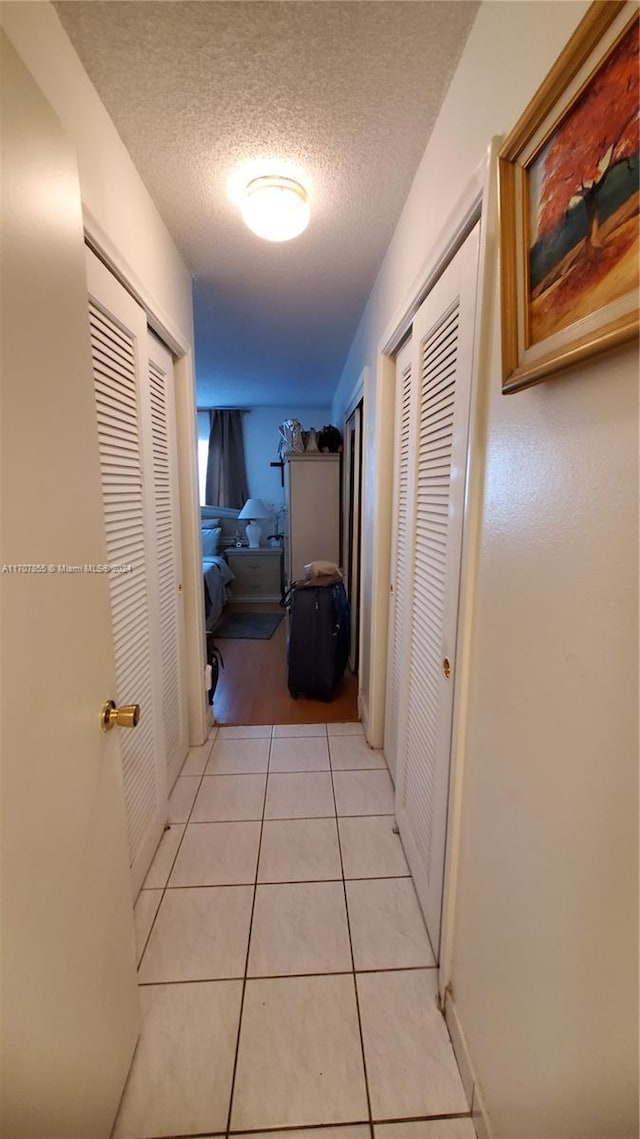 hallway featuring light tile patterned floors and a textured ceiling