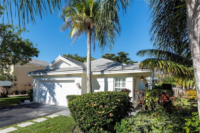 view of front of property with a tile roof, driveway, an attached garage, and stucco siding