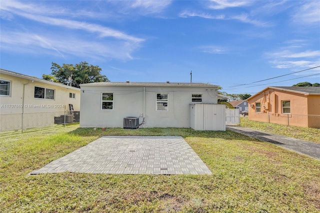 rear view of property featuring central AC unit, a patio area, and a yard