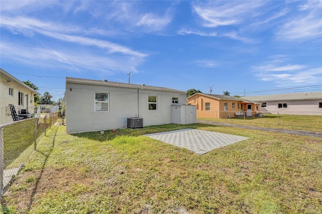 rear view of property with a lawn, cooling unit, and a patio