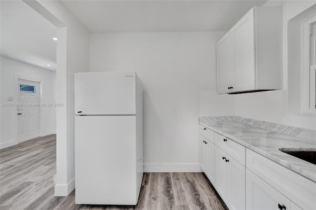 kitchen featuring light stone countertops, white fridge, white cabinetry, and light hardwood / wood-style floors