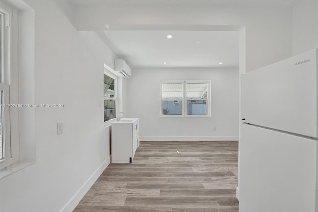 hall featuring sink, a wall unit AC, and light hardwood / wood-style flooring