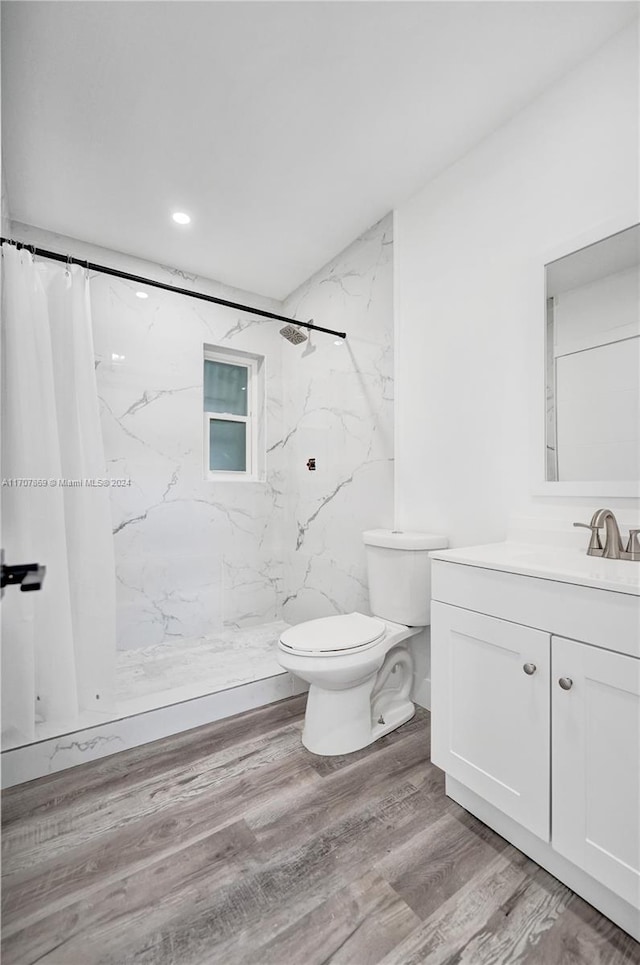 bathroom featuring wood-type flooring, vanity, toilet, and curtained shower