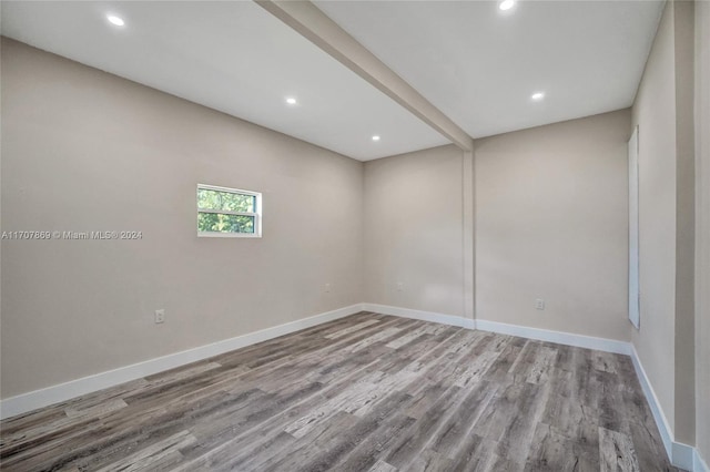 empty room featuring beamed ceiling and light hardwood / wood-style floors