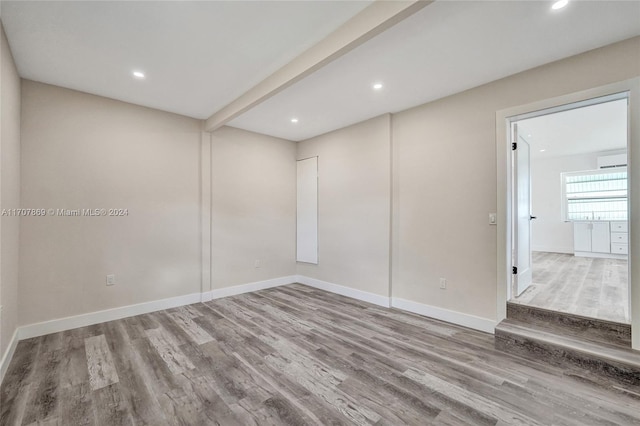 unfurnished room with beam ceiling and wood-type flooring