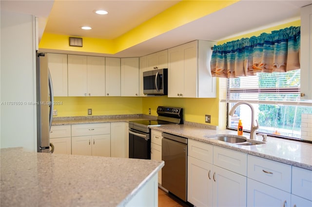 kitchen with white cabinets, light stone counters, sink, and appliances with stainless steel finishes