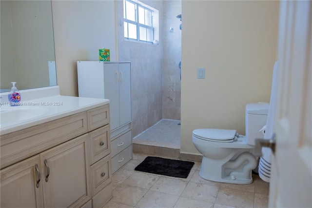 bathroom with toilet, vanity, and tiled shower