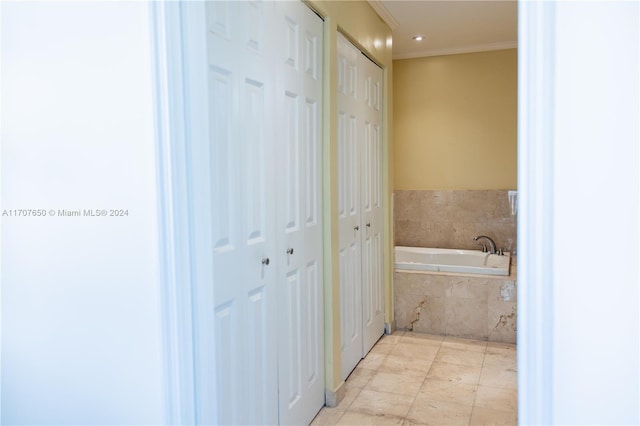 bathroom with tile patterned flooring, a relaxing tiled tub, and crown molding