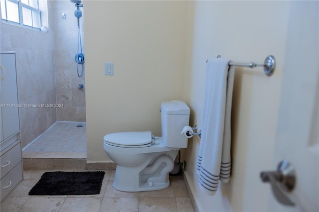 bathroom with a tile shower and toilet