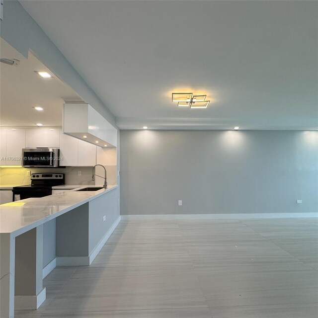 kitchen with black electric range, white cabinets, kitchen peninsula, and sink