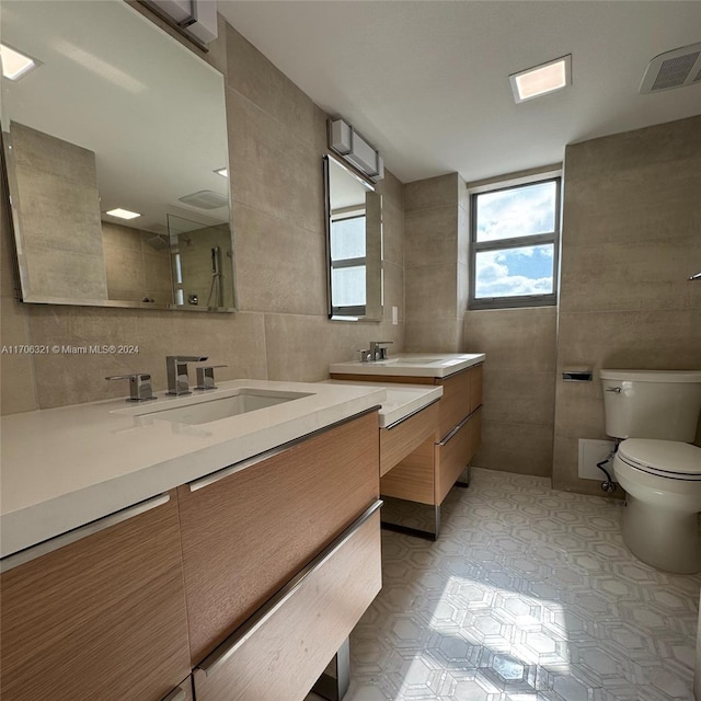 bathroom with vanity, toilet, tile walls, and walk in shower