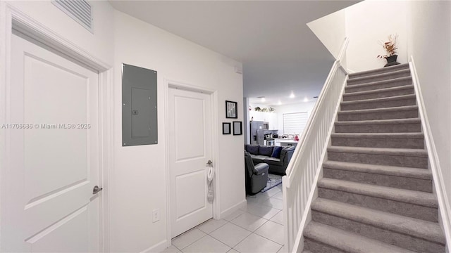 staircase featuring electric panel, visible vents, and tile patterned flooring