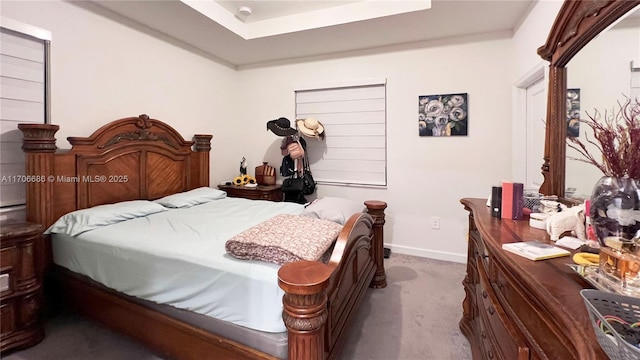 bedroom with baseboards, a raised ceiling, and carpet flooring