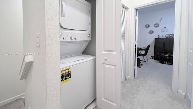 clothes washing area with laundry area, light colored carpet, and stacked washer and clothes dryer