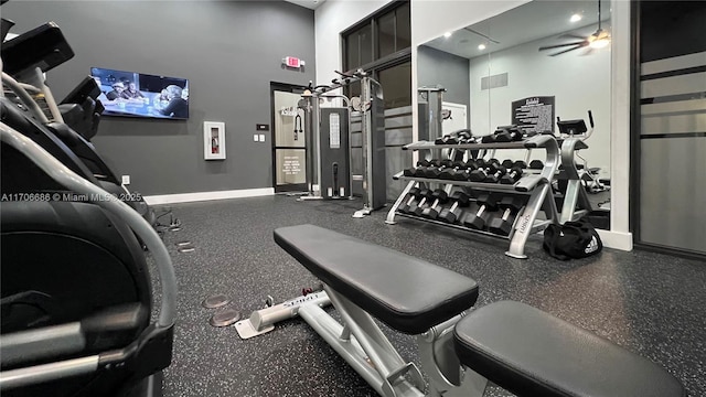 workout area featuring visible vents, baseboards, ceiling fan, and a towering ceiling