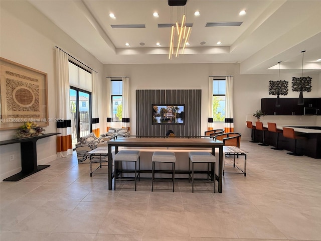 dining space with visible vents, a healthy amount of sunlight, and a tray ceiling