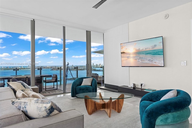 living room with carpet flooring, a water view, and a wall of windows