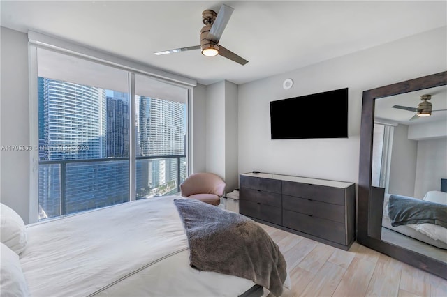 bedroom featuring ceiling fan, light hardwood / wood-style floors, and multiple windows