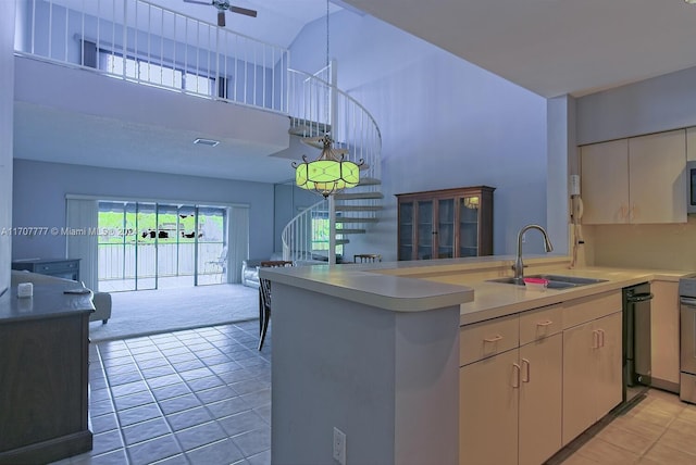 kitchen with a high ceiling, sink, appliances with stainless steel finishes, light colored carpet, and kitchen peninsula