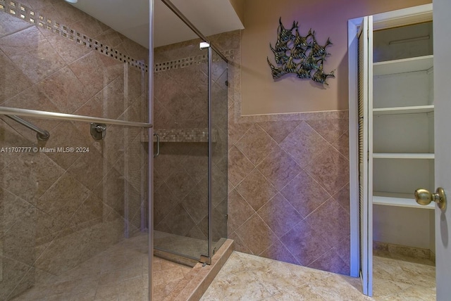 bathroom with a shower with door and tile walls