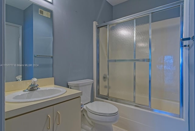 full bathroom featuring tile patterned floors, vanity, bath / shower combo with glass door, and toilet