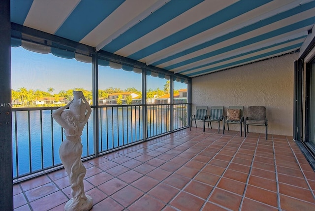 unfurnished sunroom featuring beamed ceiling and a water view