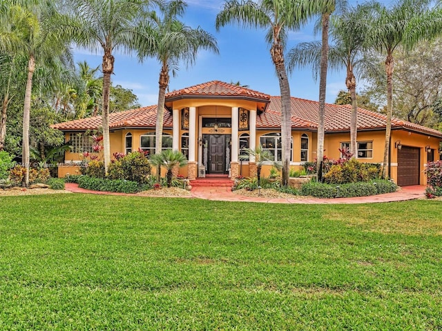 mediterranean / spanish-style home with a garage, a front yard, a tile roof, and stucco siding