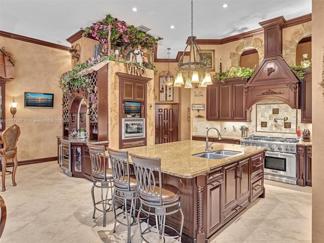 kitchen featuring an island with sink, ornamental molding, light stone countertops, high end stove, and a sink