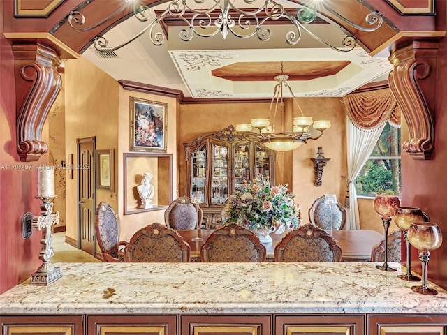 interior space with ornate columns, a notable chandelier, pendant lighting, crown molding, and light stone counters