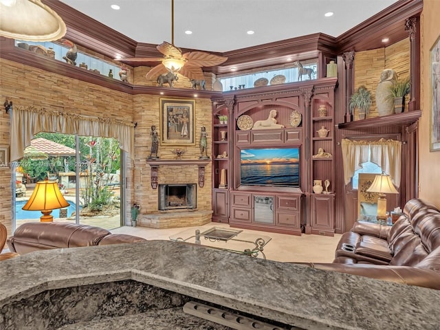 living area featuring recessed lighting, ceiling fan, crown molding, and a stone fireplace