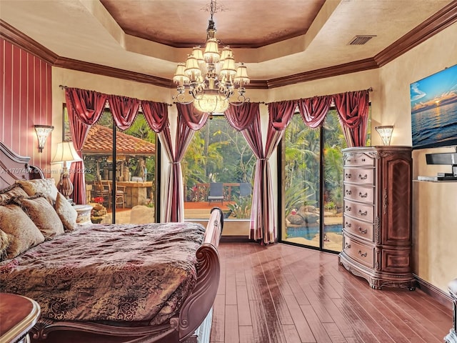 bedroom featuring wood-type flooring, a tray ceiling, access to outside, and a notable chandelier