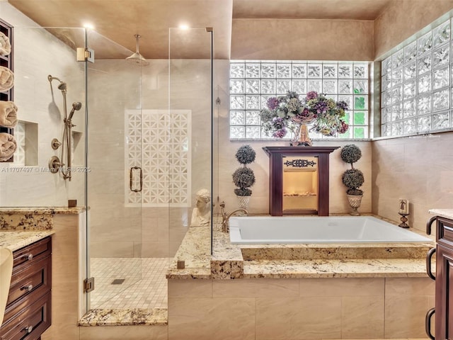 bathroom featuring tile walls, vanity, and shower with separate bathtub