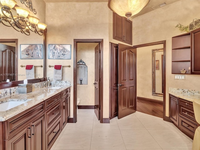 bathroom with toilet, an inviting chandelier, tile patterned floors, and vanity